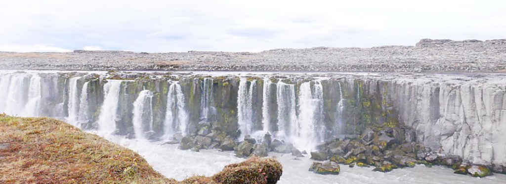 dozens of waterfalls in Iceland falling from a flat plain into a river