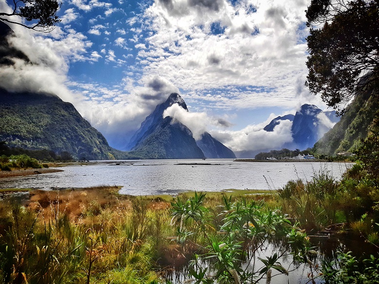 boggy water with cliffs jutting out of it into the clouds