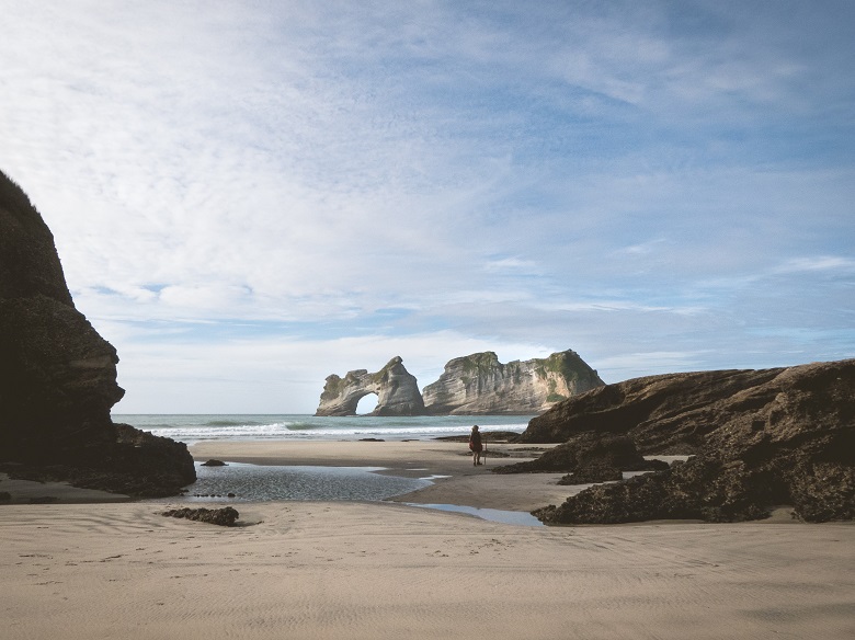 sandy beach with arch in background