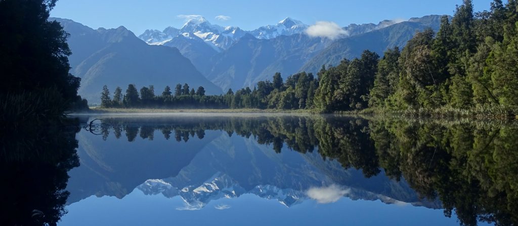 snowy mountain range reflected in lake