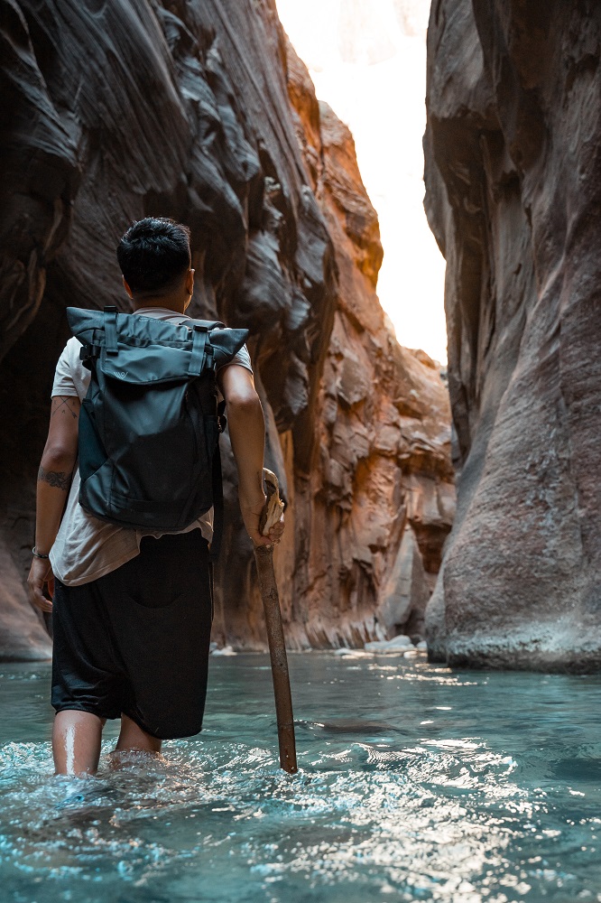Person walking in clear water between tall rock walls