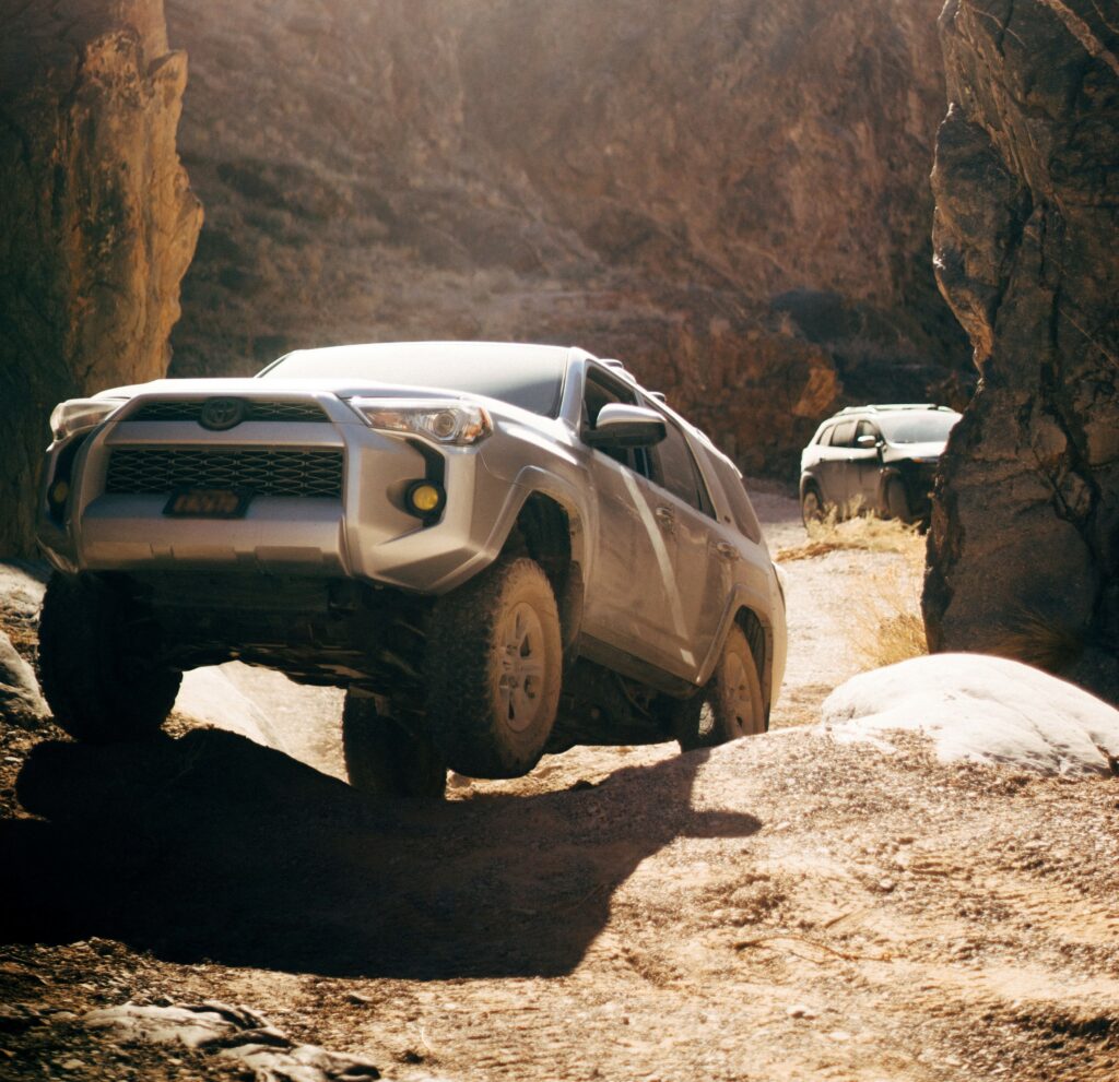 SUV driving in desert with a wheel off the ground