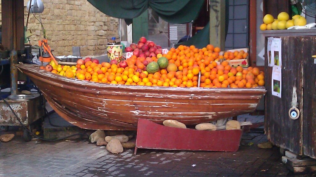 oranges, pomegranates, and other fruit in a broken wooden boat on shore
