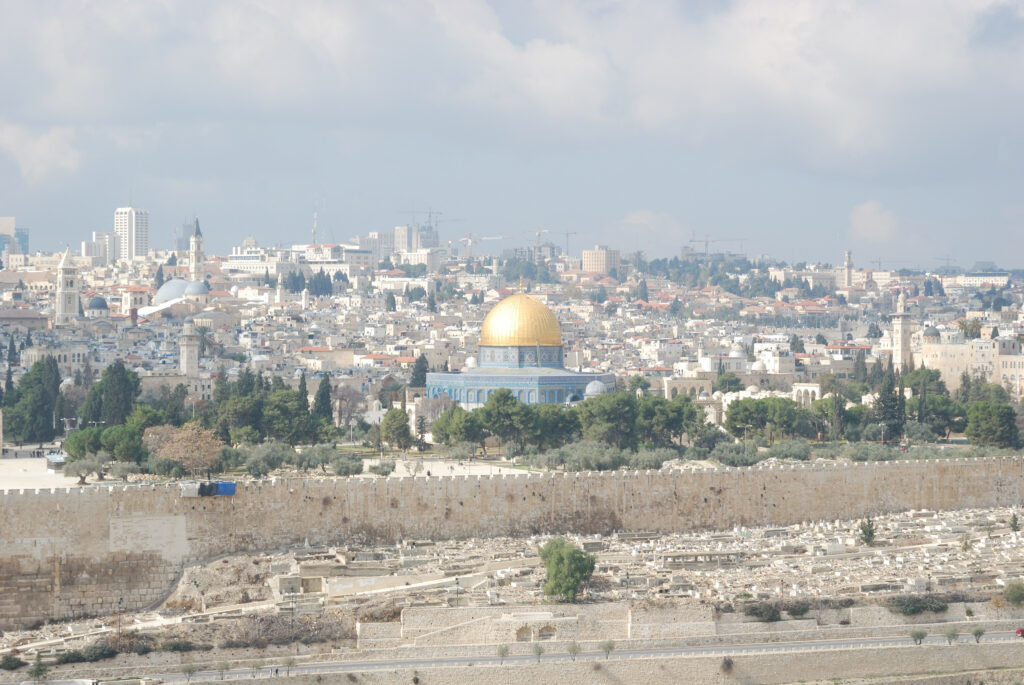 golden dome on blue building surrounded by trees and stone walls