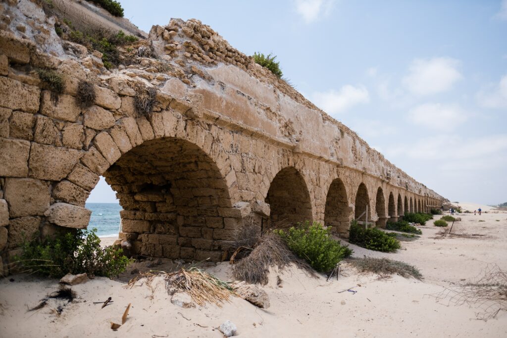 ruins of arches in stone wall on a white sand beach