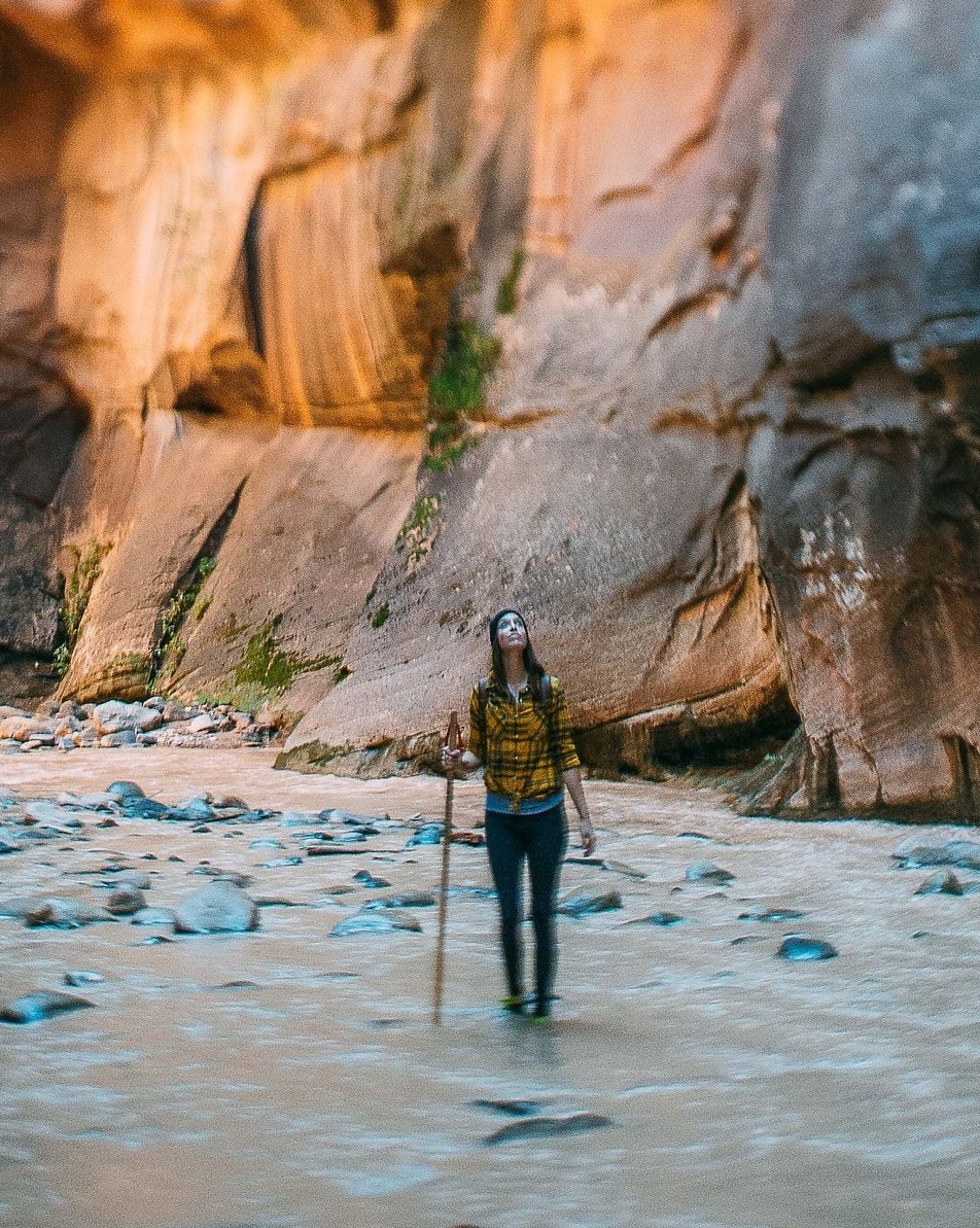 woman holding wooden staff in river looking up