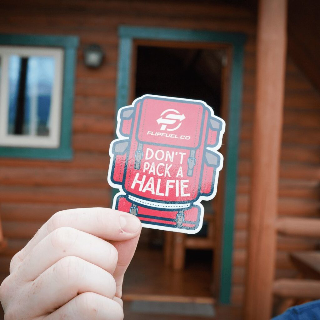 hand showing sticker in the form of red backpack saying don't pack a halfie